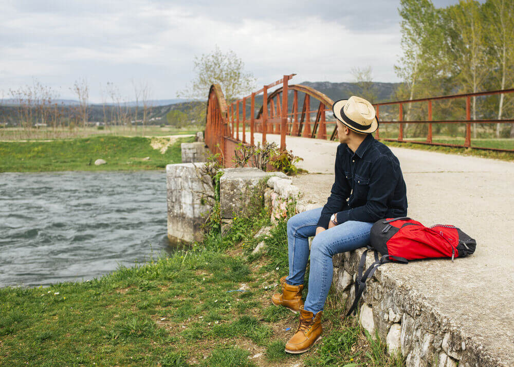 Solo traveler sitting by a scenic river for local tours