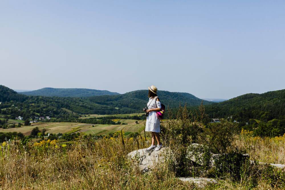 Solo travel woman with a camera on a hilltop