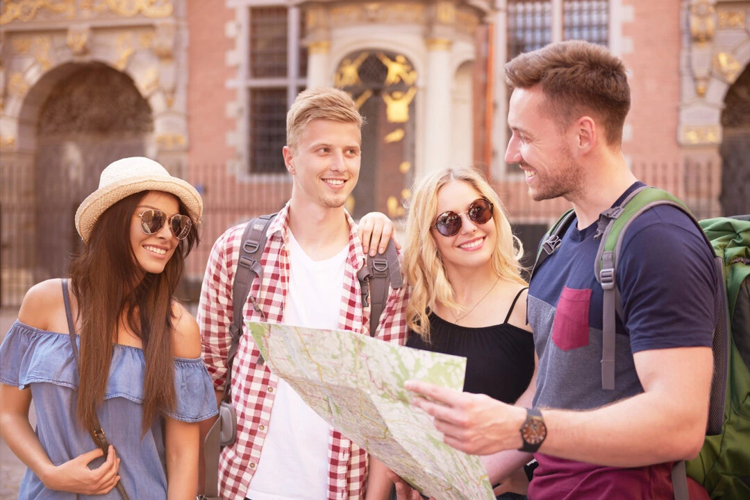 A group with a map listens to a guide near a historic, ornate building.